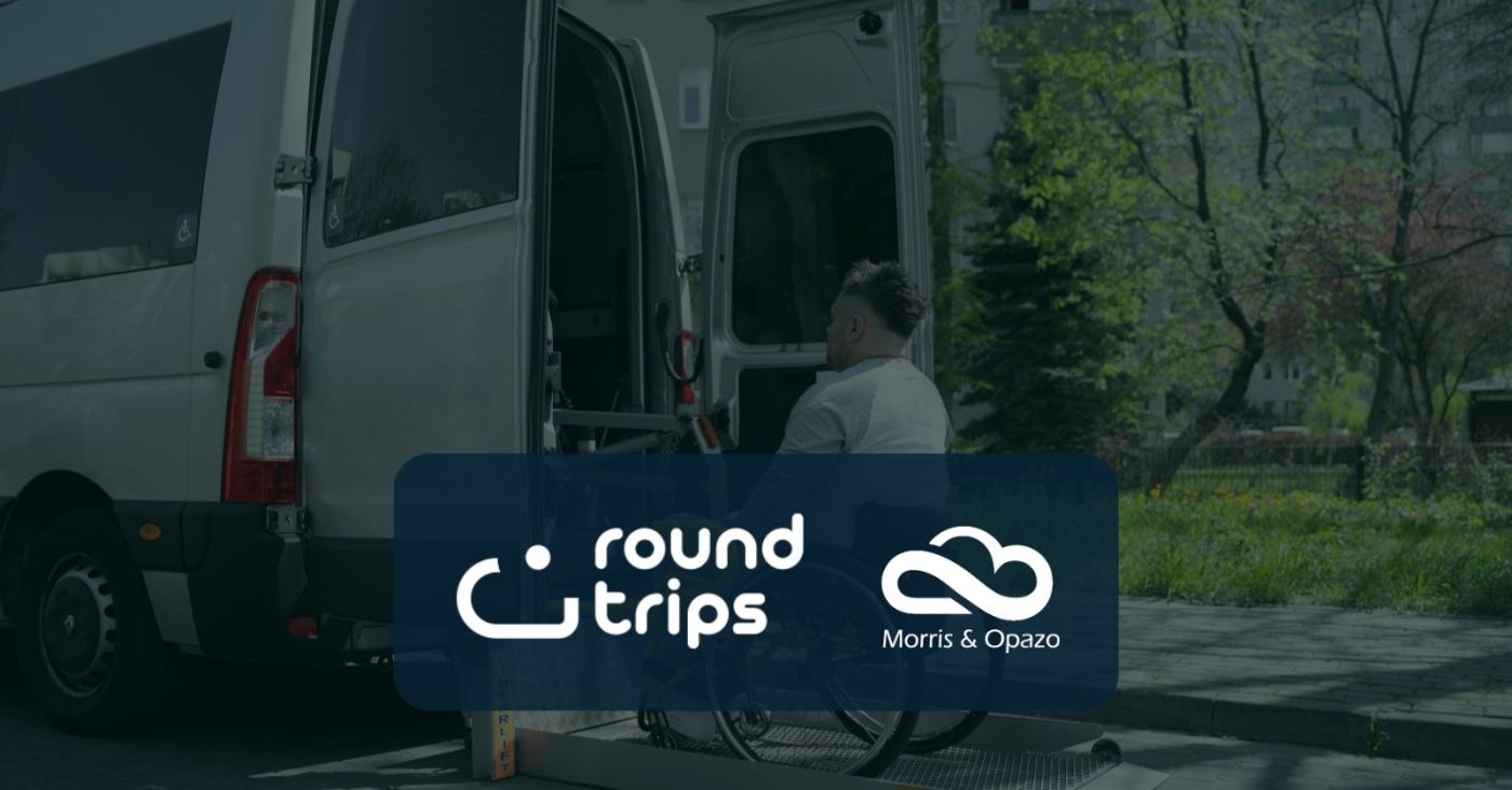 White accessibility van with open side doors and a wheelchair user entering, overlaid with Round Trips and Morris & Opazo logos on a blue panel.